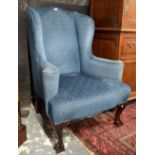 An upholstered 19th century wing armchair with shaped arms,