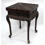 An antique Chinese hardwood envelope card table, moulded and relief carved overall with dragons,