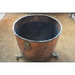 An antique copper log basket with brass lion mask ring handles, raised on three cast brass paw feet,