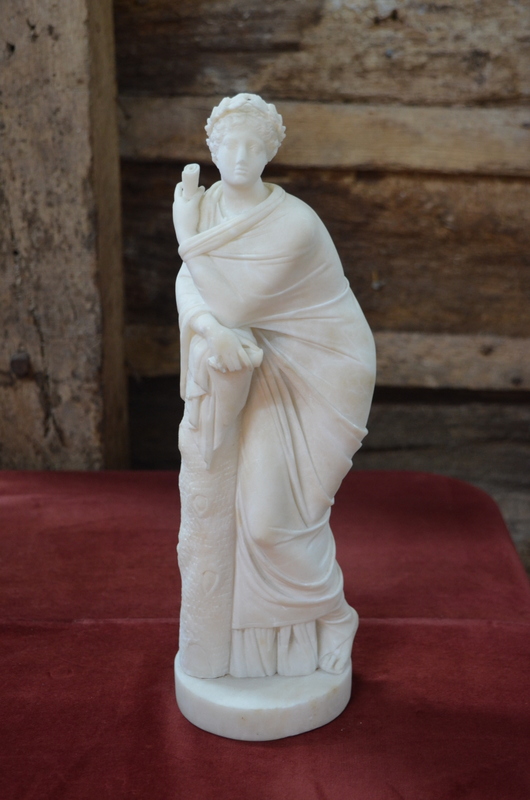 An alabaster cloaked classical figure with laurel wreath and scroll,