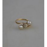 A diamond and two half pearl crossover ring, yellow and white metal set, stamped K 15,