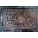 A Persian Kirman rug, traditional floral design with central motif on dark blue ground,