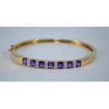 A 9ct yellow and white gold hinged bangle set with seven sugar loaf amethysts,