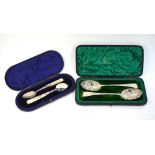 A cased pair of late Victorian silver serving spoons with ornately embossed and chased bowls and