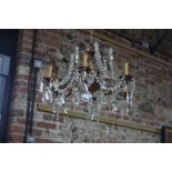 An ornate brass six-branch electrolier hung with facetted drops and beads,
