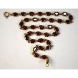 A garnet necklace of thirty-four claw set garnets in yellow metal setting stamped 9k,