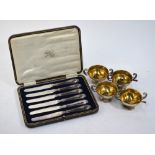 A set of four open salts with gilt interiors, twin scroll handles and stemmed foot-rims,