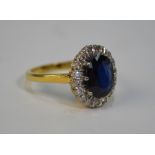 A sapphire and diamond cluster ring, the oval central sapphire surrounded by eighteen diamonds,