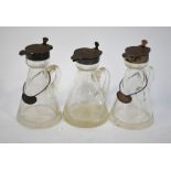 A pair of conical glass whisky noggins with star-cut bases and silver collars and covers,