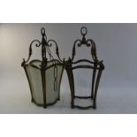 A pair of old patinated gilt framed hanging lanterns with shaped glass panelled sides,