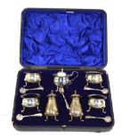 An Edwardian cased silver seven-piece condiment set with five spoons and four blue glass liners,