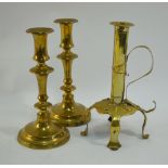 An Arts & Crafts brass candlestick with scrolling strap handle, on three raised feet,