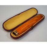 A pressed amber cheroot holder with gold band, in fitted case, approx 10 cm excluding gold band,