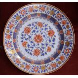 A large German circular dish, decorated in the Imari style with floral designs in orange,