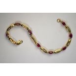 A yellow metal linked bracelet stamped 10k, set with eight oval rubies,