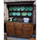 An 18th century country oak dresser, the plank back rack with moulded cornice over two shelves,