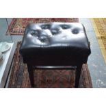 An ebonised buttoned black leather seat adjustable piano stool