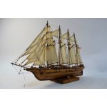 A small solid hull wood model of a four-masted sailing ship,