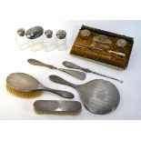 Four cut glass toilet jars with engraved silver covers, with a pair of hairbrushes,