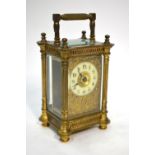 A brass carriage clock with ornate gilt surround to the ivorine dial, flanked by fluted pillars,