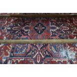 A Persian Heriz carpet, the large central blue medallion on red ground with stylised floral design,