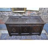 A 17th/18th century oak coffer, the triple panelled hinged top over a conforming carved panel front,