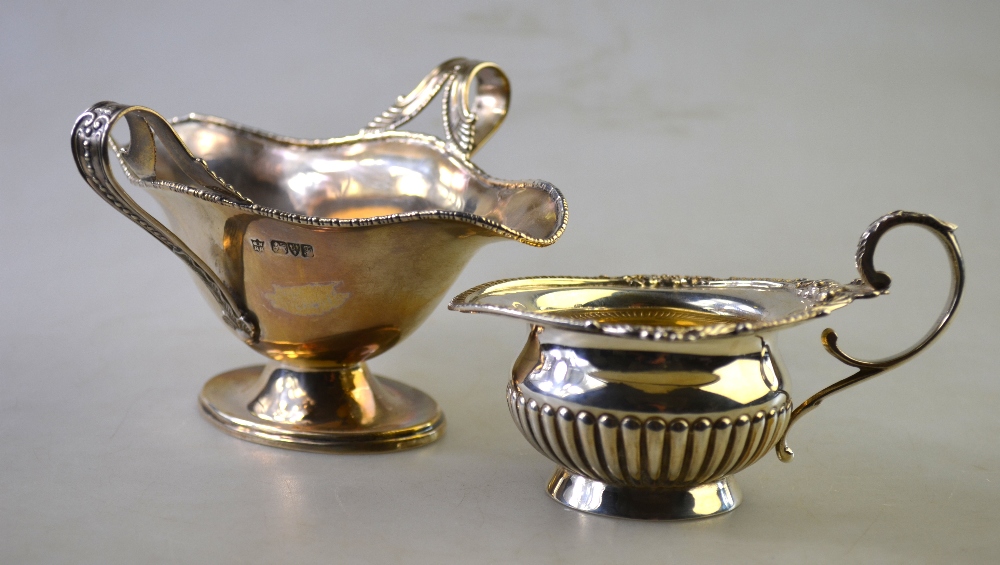 A small late Victorian silver half-reeded cream jug with decorative rim and scroll handle,