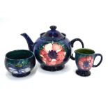 A Moorcroft three piece tea set decorated in the anemone pattern on a blue/green ground,