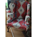 A George II style wingback armchair in kelim upholstery,