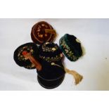 Five early 20th century smoking hats comprising; a black velvet floral embroidered hat with tassel,