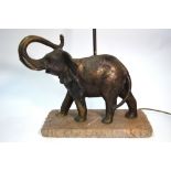 A cast bronze elephant table lamp raised on a rough stone composite base,