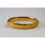 A 9ct yellow gold half engraved bangle,