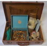 A vintage suitcase containing numerous lace-making bobbins, cylinder with part-made length of lace,