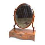 A Victorian cross-banded mahogany oval toilet mirror on a serpentine three drawer base,