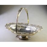 A Sheraton revival oval silver fruit basket with swing handle, pierced decoration and raised foot,