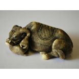 A stained ivory netsuke with large himotoshi, carved as a recumbent water buffalo beside its calf,