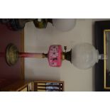 A Victorian oil lamp with floral-painted pink glass reservoir and pillar,