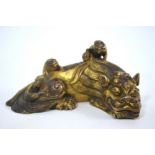 A gilded metal scroll weight designed as a recumbent mythological animal, 6.