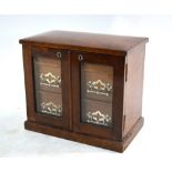 An Edwardian table top cabinet having a hinged top enclosing two storage wells over a pair of