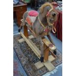 A faux pony skin covered wooden rocking horse on square pillar safety stand,