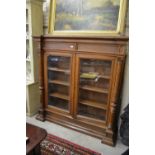 A Victorian heavy oak bookcase with twin glazed doors enclosing adjustable shelves,