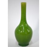 A lime green monochrome bottle vase with tall cylindrical neck and oviform body on circular foot,