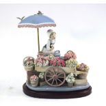 A Lladro figural group - flower seller with wheelbarrow, baskets and pails of flowers,