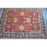 An Indian Agra carpet with large floral motifs linked by scrolling tendrils on red ground,