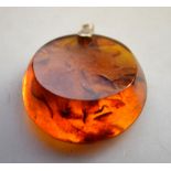A circular amber pendant, gilt metal fitting,
