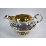 A George IV silver octagonal cream jug of organic form, with floral-cast scroll handle,