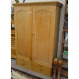 A Victorian waxed pine wardrobe with twin doors enclosing sliding shelves,