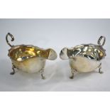 A near-matched pair of silver sauce boats with cut rims, scroll handles and pad feet,
