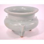 A celadon monochrome incense burner with circular, everted rim and tripod legs, 13cm diameter,