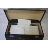 A sarcophagus-shaped case containing damask, crocheted-edge, drawn-threadwork and other tablecloths,
